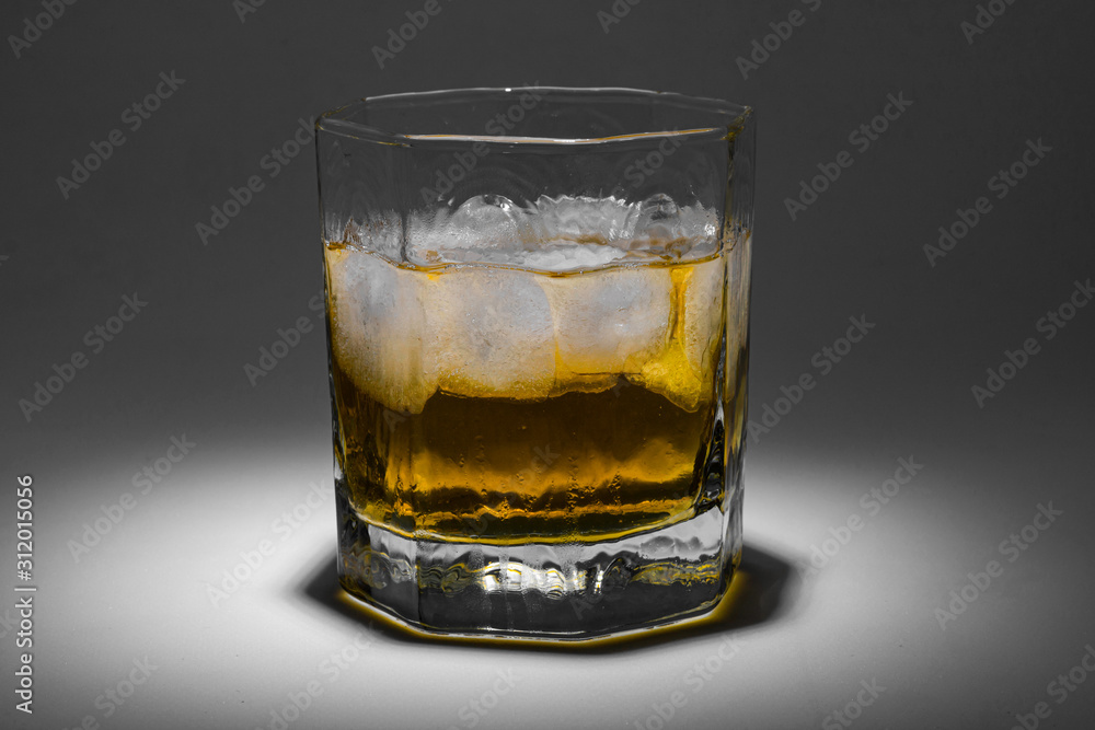 A glass of whiskey with ice. Art installation with lighting from above and close-up. A glass of whiskey with ice. Art installation with lighting from above and close-up.