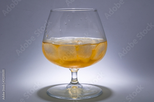 A glass of whiskey with ice. Art installation with lighting from above and close-up.