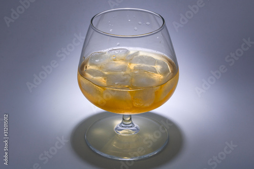 A glass of whiskey with ice. Art installation with lighting from above and close-up.