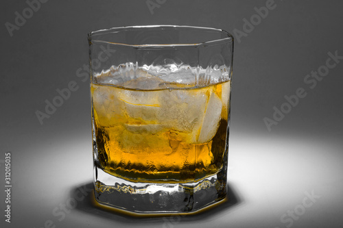 A glass of whiskey with ice. Art installation with lighting from above and close-up.