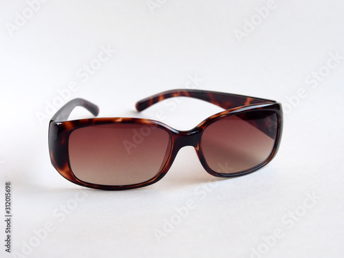Brown-rimmed sunglasses, women's accessory. Summer season, sea, beach.