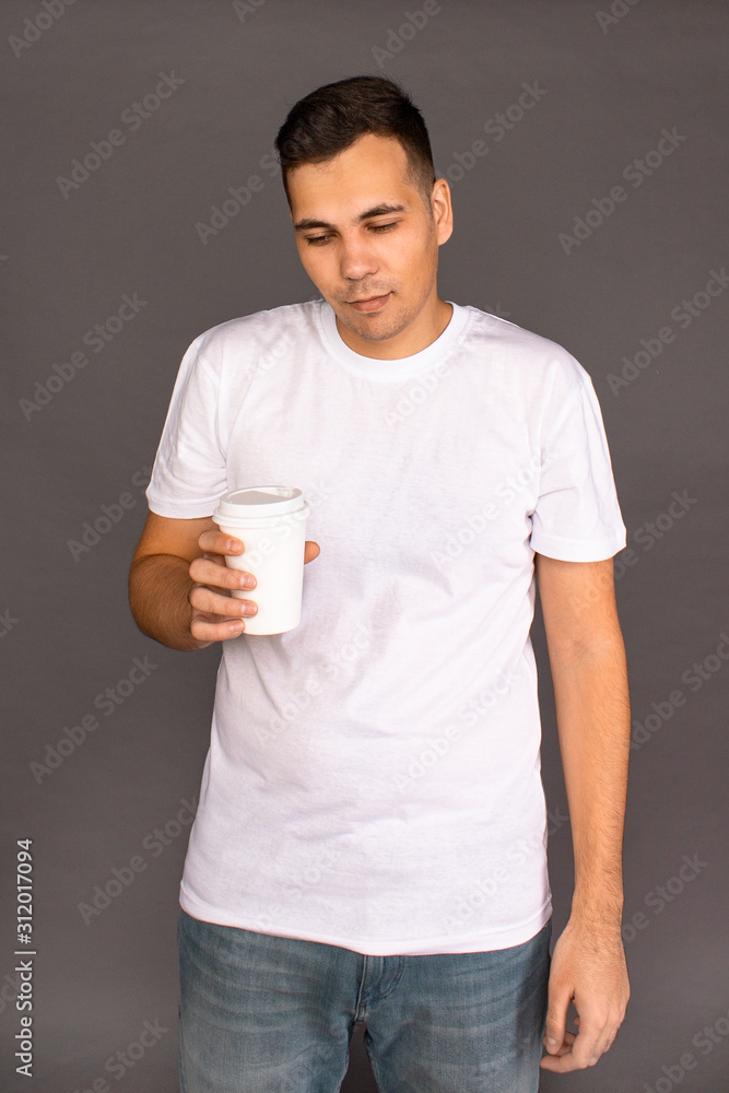 A guy in a white t-shirt is drinking coffee and trying to Wake up and cheer up. A guy in a white t-shirt is drinking coffee and trying to Wake up and cheer up.
