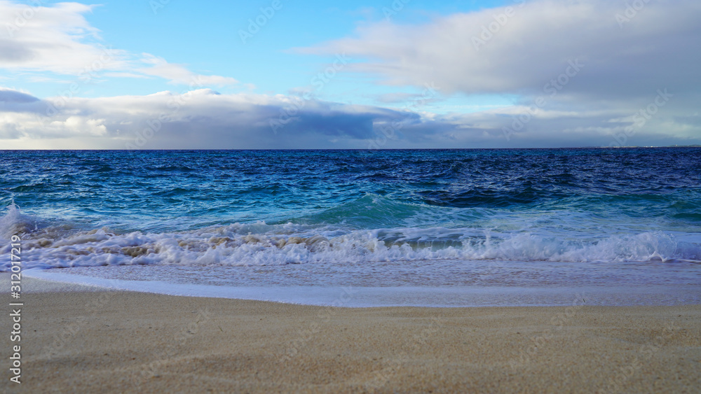 Tropical beach white sand, blue clear ocean water. sea foam on the beach on a sunny day. sea waves on the shore. surf breaking on shore at sunset Tropical beach white sand, blue clear ocean water. sea foam on the beach on a sunny day. sea waves on the shore. surf breaking on shore at sunset