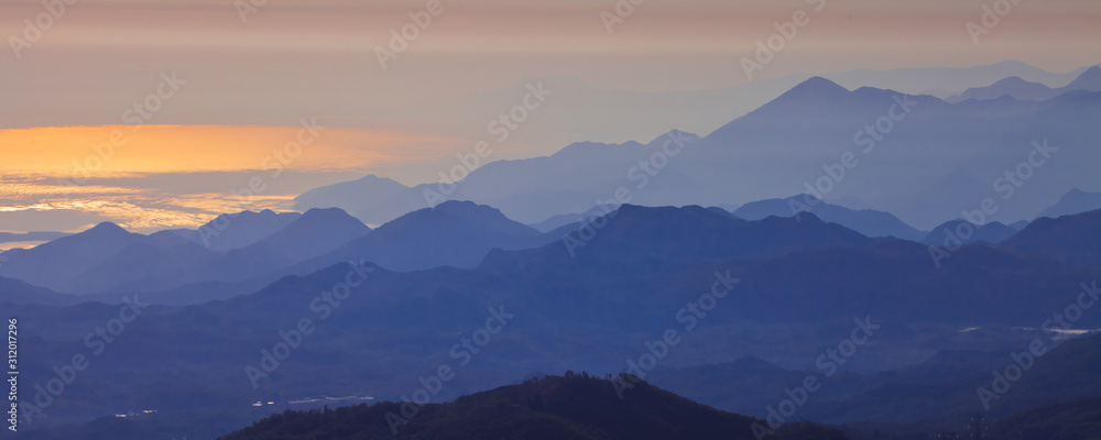  with blue misty mysterious mountains in the distance and an orange pastel sky. Distant blue mountains.