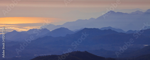 Canvas Print with blue misty mysterious mountains in the distance and an orange pastel sky