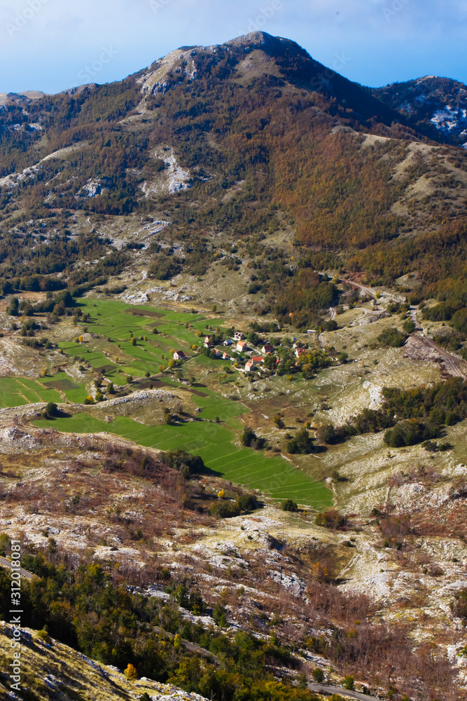  small house with a red roof among the emerald green alpine meadows and stones far below, a symbol of solitude of peace and unity with nature.