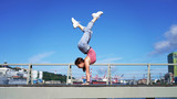 Young flexible girl in life style clothes makes a handstand on observation deck in the passenger port. beautiful gymnast twine on a background of blue sky on sunny day. back bend pose. Handstand poses