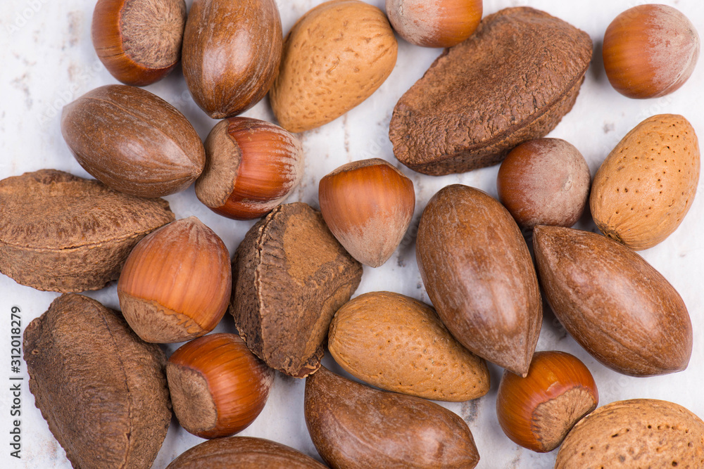 Mixed nuts, almonds, brazilnuts, pecan nuts and hazelnuts on a white textured background, empty copy space Mixed nuts, almonds, brazilnuts, pecan nuts and hazelnuts on a white textured background, empty copy space
