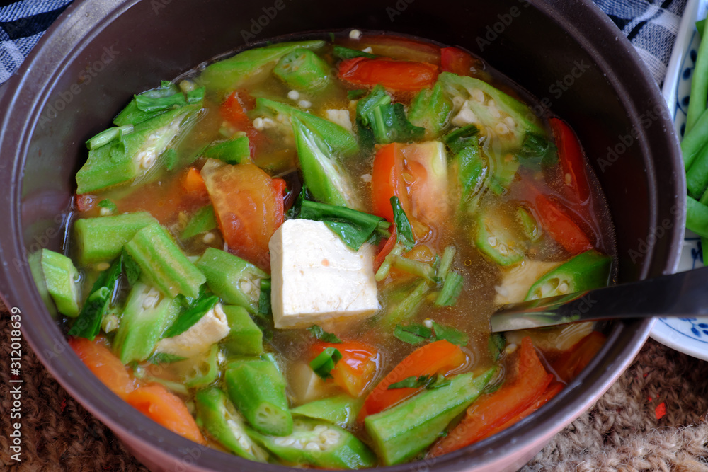 Vietnamese vegan soup in pot from vegetables are okra, tofu, tomato Vietnamese vegan soup in pot from vegetables are okra, tofu, tomato