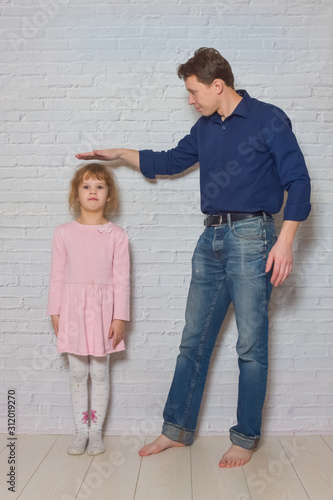 father and daughter against a white brick wall