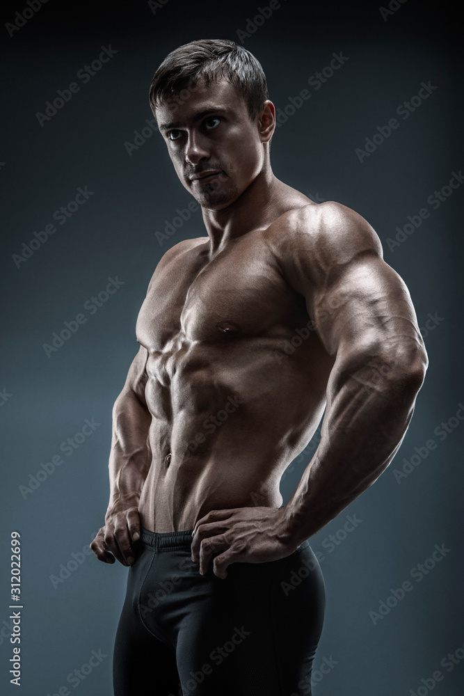 Muscular and fit young bodybuilder fitness male model posing over black ...