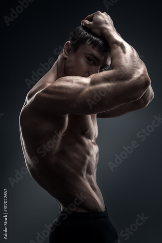 Handsome muscular bodybuilder preparing for fitness training. Studio shot on black background.