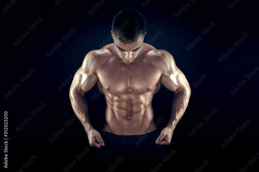 Strong athletic man fitness model torso showing six pack abs, perfect abs, shoulders, biceps, triceps and chest. Isolated on black background.