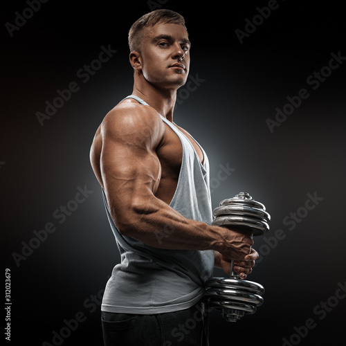 Strong athlete in activewear ready to doing pumping up muscles with dumbbell, confidently looking forward. Power bodybuilder with biceps, triceps and chest