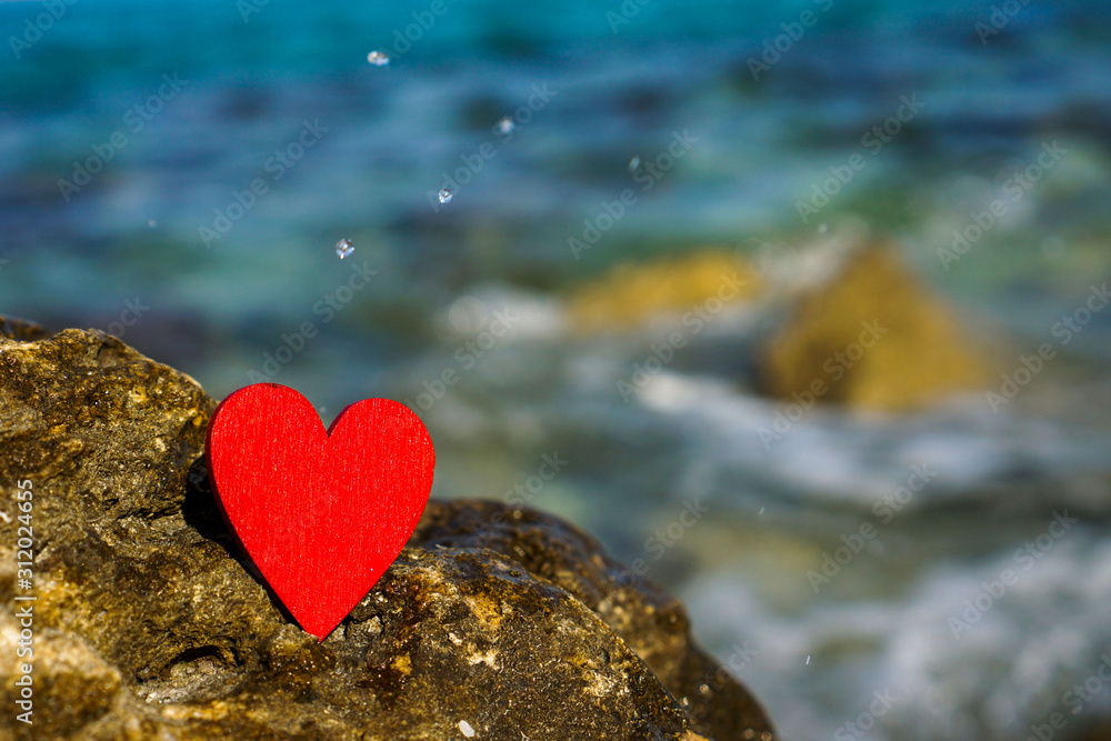 Fototapeta premium red heart on a stone in front of blue sea