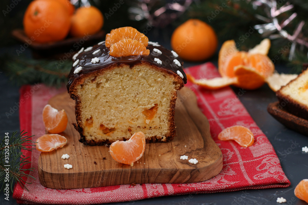Cupcake with tangerines, covered with chocolate glaze is located on the New Year's background, Festive still life Cupcake with tangerines, covered with chocolate glaze is located on the New Year's background, Festive still life