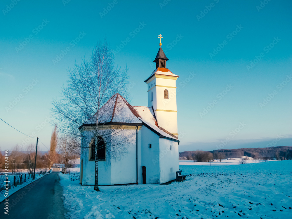Kapelle in winterlicher Landschaft in Voralpenregion mit Weg
