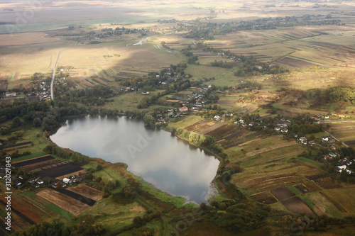 Aerial view of farmland area landscape and lake from airplane. Landscape with lake. Environment protection. Drone flight. view of the village from the sky. photo with noise