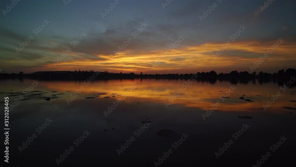 Vdo. Aerial view evening above the lake, view of yellow sun light with reflection on surface of water and cloudy sky background, twilight at Krajub reservoir, Ban Pong District, Ratchaburi, Thailand. Vdo. Aerial view evening above the lake, view of yellow sun light with reflection on surface of water and cloudy sky background, twilight at Krajub reservoir, Ban Pong District, Ratchaburi, Thailand.