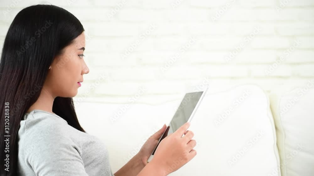 Asian woman using ipad shopping online website on smartphone with smiling face. Happiness asian woman holding cellphone checking mail from online shopping website read article Blog vlog social media Asian woman using ipad shopping online website on smartphone with smiling face. Happiness asian woman holding cellphone checking mail from online shopping website read article Blog vlog social media