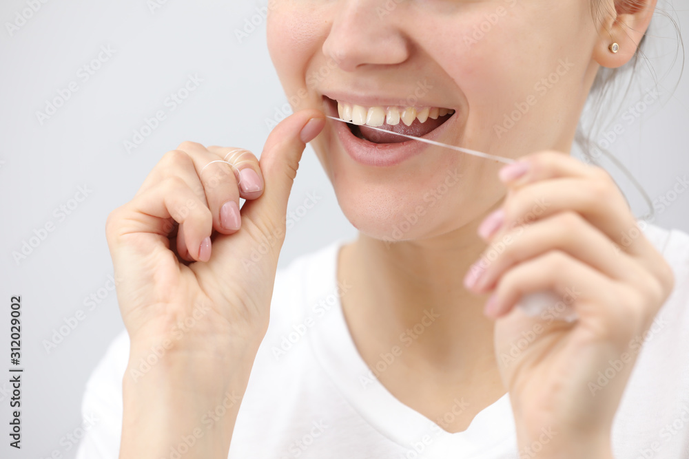 Oral hygiene and health care. Smiling women use dental floss of white healthy teeth on a white background. place for inscription Oral hygiene and health care. Smiling women use dental floss of white healthy teeth on a white background. place for inscription