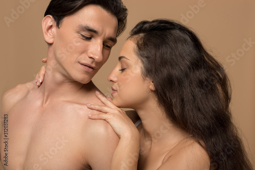 beautiful tender girl hugging young boyfriend isolated on beige