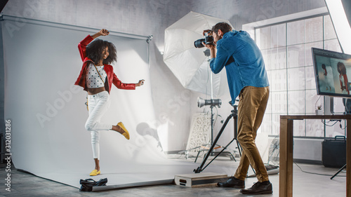 Behind the Scenes on Photo Shoot: Beautiful Black Model Poses for a Photographer, he Takes Photos with Professional Camera. Stylish Fashion Magazine Photoshoot done with Pro Equipment in a Studio photo