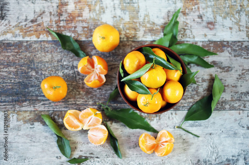Selective focus. Ripe juicy tangerines with leaves in a bowl. Peeled tangerines. Tangerines in a peel.