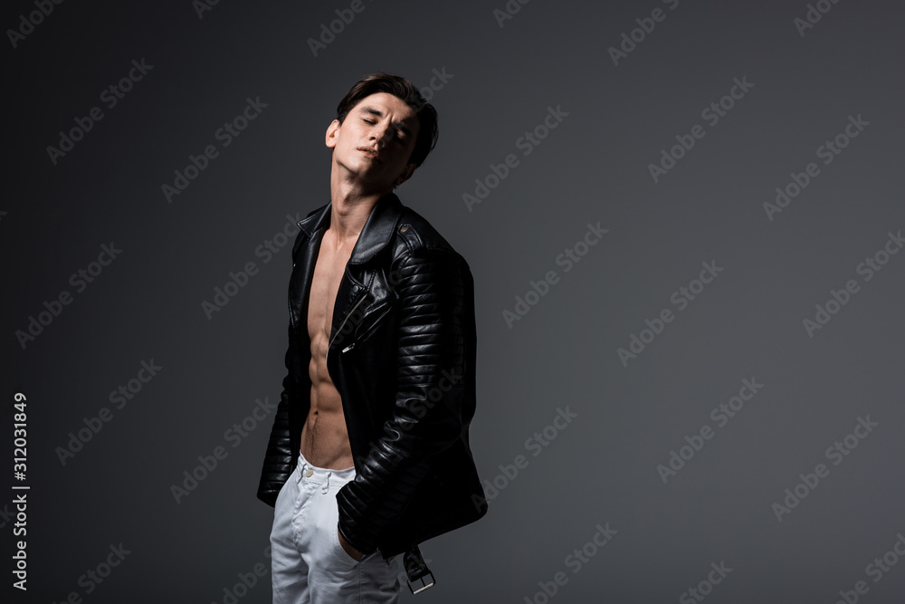 Obraz premium stylish sexy man in white jeans and black leather jacket, isolated on grey