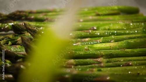 oiling fresh green asparagus stems with the brush before baking close up