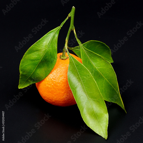 Ripe juicy orange mandarin with leaves isolated on a black background
