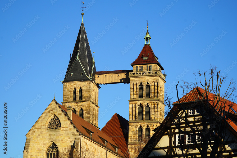 Obraz premium Die beiden Türme der Stadtkirche St. Dionys im Esslingen. Die Brücke stabilisiert den schiefen Tum. Im Fordergrund ein altes Fachwerkhaus