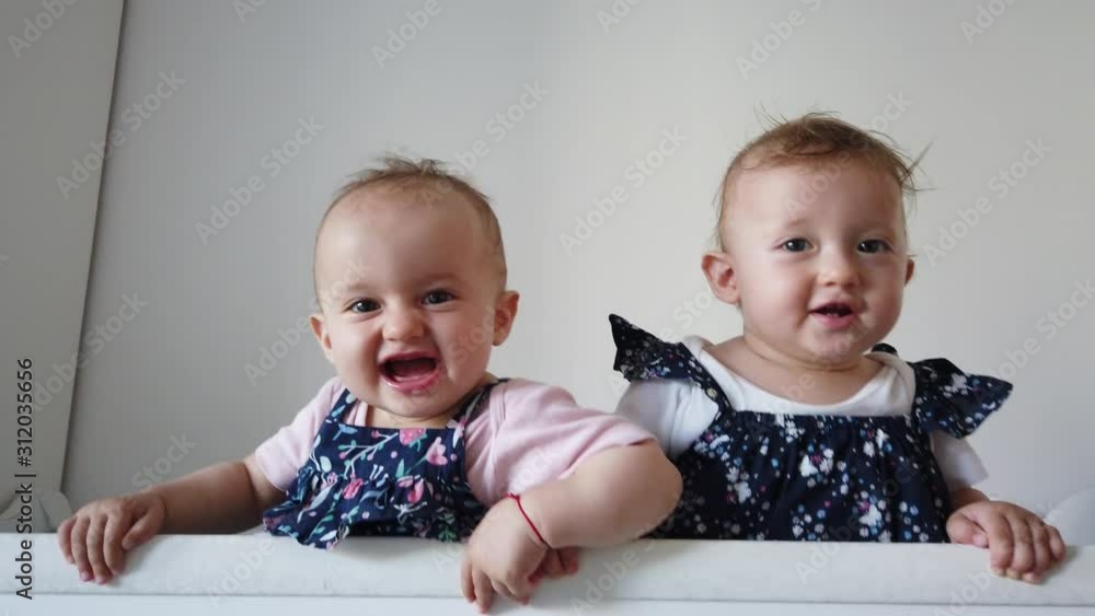 Two fraternal twins sisters having fun in crib. Two babies standing in crib. Two fraternal twins sisters having fun in crib. Two babies standing in crib.