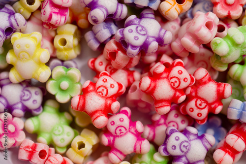 Colorful beads in the form of bears and flowers for making jewelry shot close-up on a white background