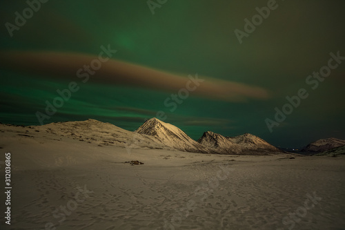 Dramatic polar lights  Aurora borealis with many clouds and stars on the sky over the mountains in the North of Europe - Tromso  Norway.long shutter speed.