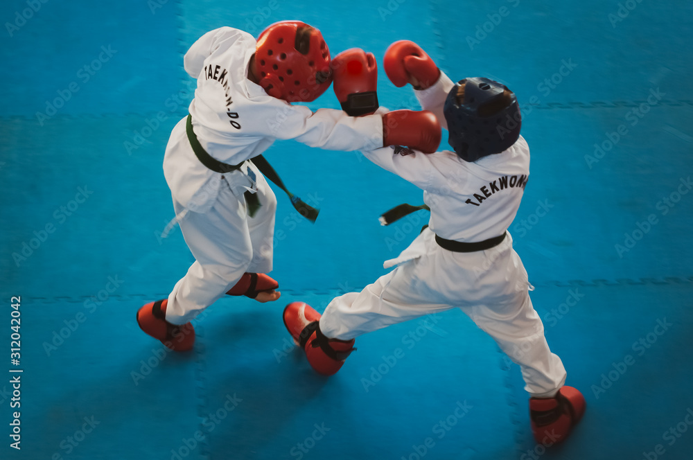 Martial Arts - Taekwondo. Kids in traditional kimano, hard hats and gloves. Sports duel. For atmospheric added film noise effect. Text: Taekwondo is the name for martial art.