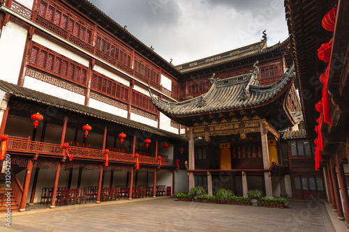 Beautiful, traditional building with red lanterns in Yu Garden, Shanghai, China, under a moody, cloudy sky