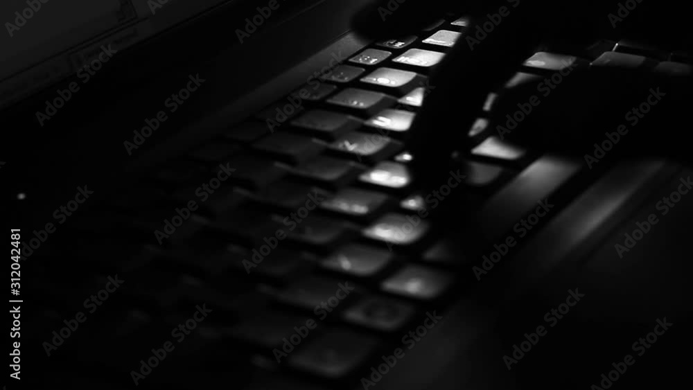 Close up of a male fingers, typing on the keyboard in the darkness.
