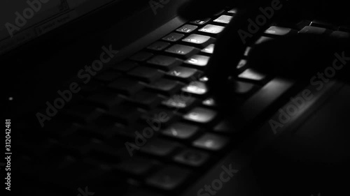 Close up of a male fingers, typing on the keyboard in the darkness.