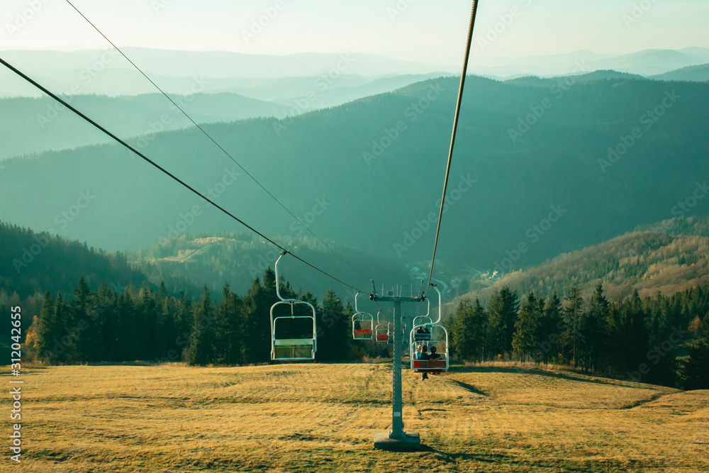 ski lift in the mountains. Beautiful sunny landscape with mountains. Blue sky, grass and forest. Background or wallpaper.