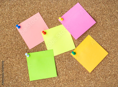 Cork board with several colorful blank notes with pins