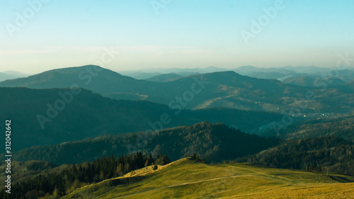 Fototapeta Naklejka Na Ścianę i Meble -  Beautiful sunny landscape with mountains and trees. Blue sky, grass and forest. Background or wallpaper.