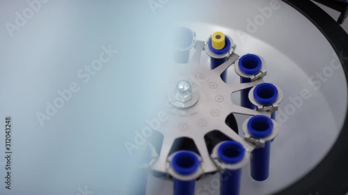 Close up shot of hands of unrecognizable laboratory worker placing test tubes with blood samples into centrifuge and turning it on