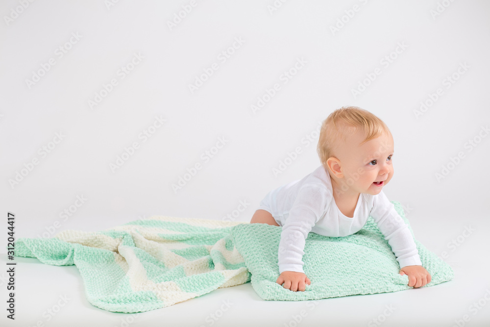 Kid boy crawling on the plush striped double colored blanket on the white background Kid boy crawling on the plush striped double colored blanket on the white background