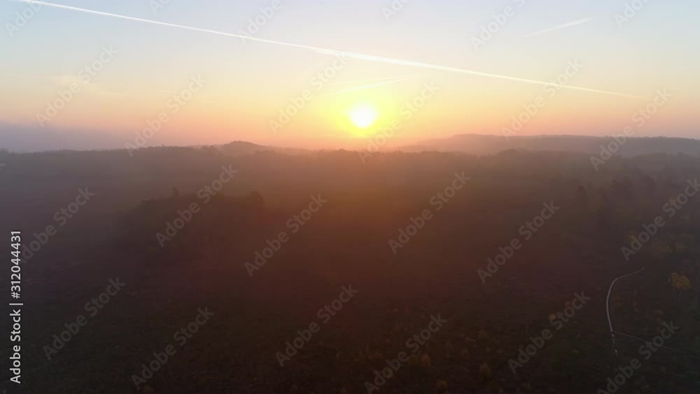 Aerial view of sunrise over foggy landscape. Drone shot flying over bog wetlands and misty forest, beautiful sky and sun, fall time. Nature autumn mountains background in 4K resolution Aerial view of sunrise over foggy landscape. Drone shot flying over bog wetlands and misty forest, beautiful sky and sun, fall time. Nature autumn mountains background in 4K resolution