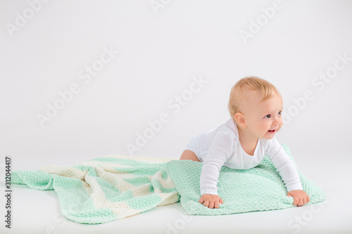 Kid boy crawling on the plush striped double colored blanket on the white background
