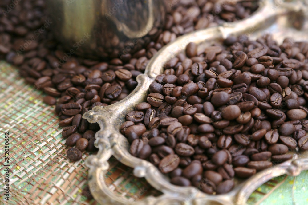Fototapeta premium Coffee grains one-to-one rare roasting and hand-picked coffee on a gold tray on a sack against the background of a turk
