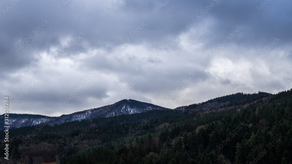 Germany, Dark clouds over mountainous black forest nature landscape in winter season with snow on peaks of mountains Germany, Dark clouds over mountainous black forest nature landscape in winter season with snow on peaks of mountains
