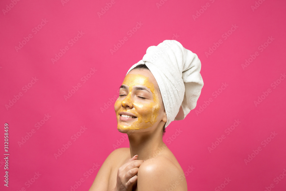 Beauty portrait of woman in white towel on head with gold nourishing mask on face. Skincare cleansing eco organic cosmetic spa relax concept. Beauty portrait of woman in white towel on head with gold nourishing mask on face. Skincare cleansing eco organic cosmetic spa relax concept.