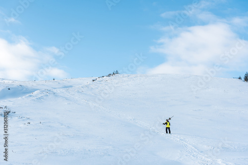 sportsman in helmet walking with ski sticks on white snow in mountains